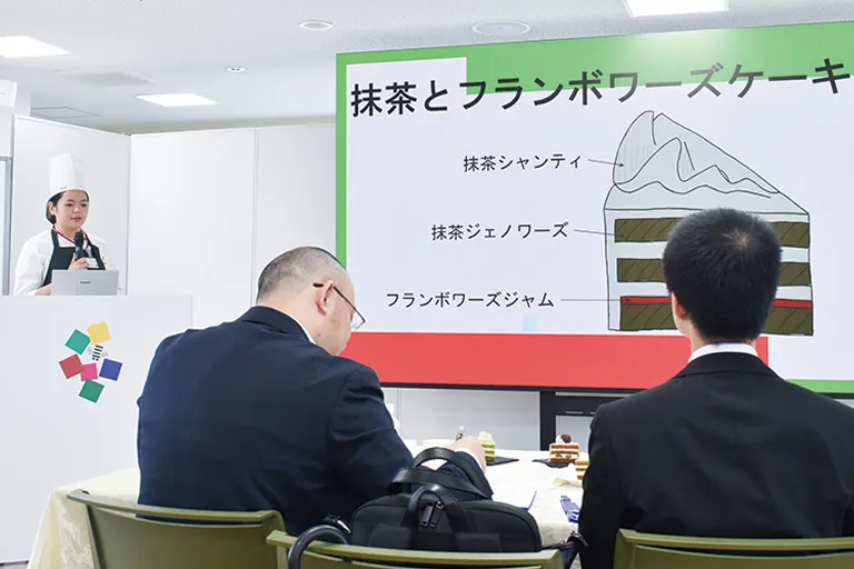学生が企業の担当者にプレゼンテーションをしている写真